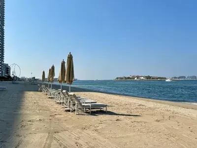 a row of chairs and umbrellas on a beach at Vogue Emaar Beachfront Grand Bleu Designed by Elie Saab, near JBR and Palm Jumeirah, Two Bedroom Apartment with Balcony and Private Beach, Access to all Amenities in Dubai