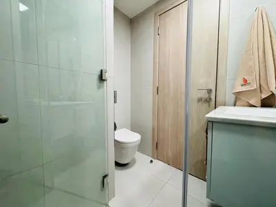 a bathroom with a toilet and a glass shower door at Mahenti - Serene & Comfortable Apartment in Dubai