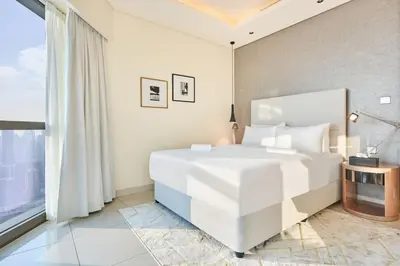 a white bedroom with a large bed and a window at Burj Khalifa View High-Floor Upgraded 3Bed Apt in Dubai