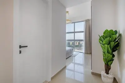 a white hallway with a potted plant and a window at Lux 3 Bedroom apartment in Marina DEC 1103 in Dubai