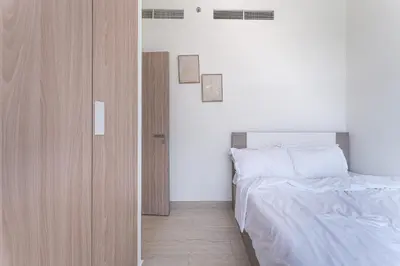 a bedroom with white walls and a bed with white sheets at HAVN - Spacious 1 bedroom in Azizi Riviera, Meydan in Dubai