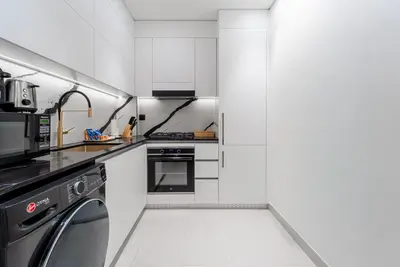 a white kitchen with a stove and a dishwasher at Studio Apartments with Private Jacuzzi - Spa - Cold Plunge - Gym in Business Bay in Dubai