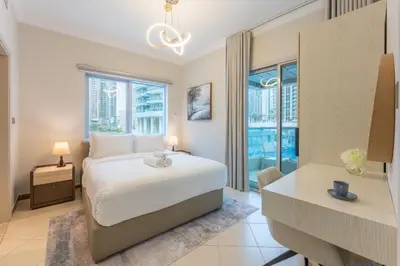 a bedroom with a bed and a desk and windows at Prestigious 2BR with nice View of Marina Dubai in Dubai