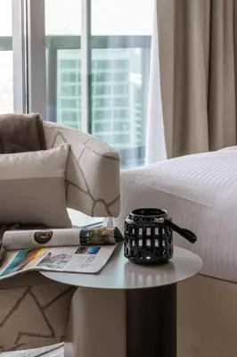 a table next to a bed with a pen and a cup at Frank Porter - Boulevard Walk Downtown in Dubai