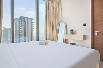 a white bed in a room with a large window at STAY BY LATINEM Luxury 1BR Plus Study Holiday Home CC 3109 Near Burj Khalifa in Dubai