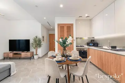 a living room with a table and chairs and a kitchen at Bespoke Holiday Homes - Elegant 2BR Waterfront Stay with Canal View in Dubai