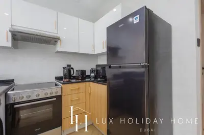 a kitchen with a stainless steel refrigerator and wooden cabinets at LUX The Marina View Suite 3 in Dubai