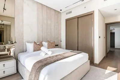 a bedroom with a large white bed and a bathroom at Luxurious Bliss - 3-BR plus maids - Grand Bleu by Elie Saab in Dubai