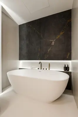 a white bath tub in a bathroom with a painting at Luxurious Bliss - 3-BR plus maids - Grand Bleu by Elie Saab in Dubai