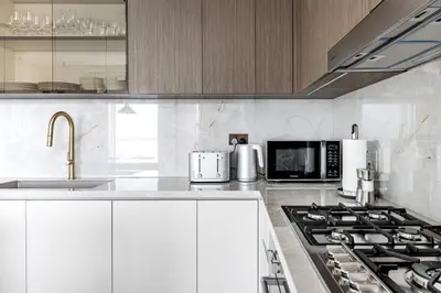 a kitchen with white cabinets and a stove top oven at Luxurious Bliss - 3-BR plus maids - Grand Bleu by Elie Saab in Dubai