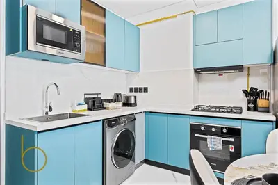 a kitchen with blue cabinets and a dishwasher at Bookable 1 Bed in Opalz by Danube in Dubai