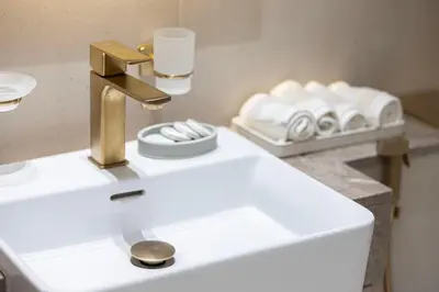 a bathroom with a sink with a gold faucet at Stylish Family Retreat That Sleeps 6 In The Heart of JVC in Dubai