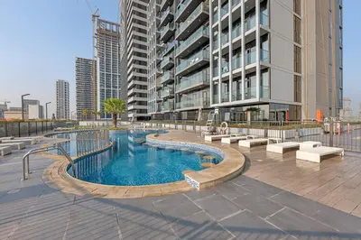 a swimming pool in front of a tall building at Lush 1BR Apt at Bloom tower in JVC in Dubai