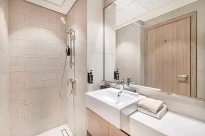 a white bathroom with a sink and a shower at Daniels Studio at Meydan with Community View in Dubai
