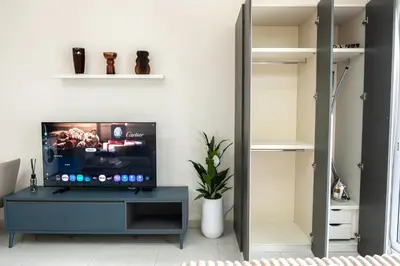 a living room with a tv and a walk in closet at Modern Studio with Balcony, Stunning City Views & Free Parking, Close to Dubai Mall in Dubai