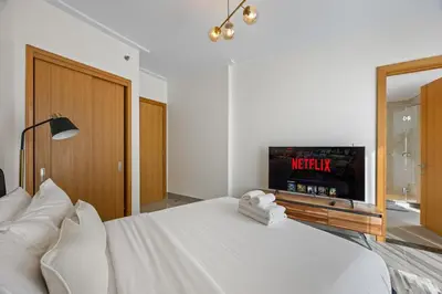a bedroom with a white bed and a tv at 2BR at Opera Grand, Fountain and Burj Khalifa Views in Dubai