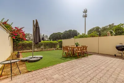 a patio with a table and chairs and an umbrella at The Springs 8 - 2 Bedroom with Maids Room Villa - Allsopp & Allsopp in Dubai