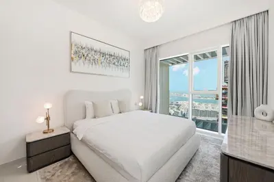 a white bedroom with a bed and a window at Cozy 1BD Apartment in Grand Bleu, Emaar Beachfront in Dubai