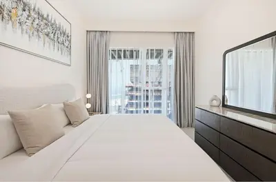 a white bedroom with a large bed and a window at Cozy 1BD Apartment in Grand Bleu, Emaar Beachfront in Dubai