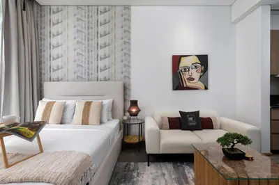 a bedroom with a white bed and a couch at Maison Privee - Serene Studio Escape with Balcony in JVC in Dubai