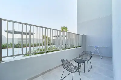 a room with two chairs and a balcony with a view at 1BR with Huge Terrace & Pool View at JVC in Dubai