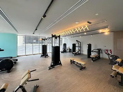 a gym with several treadmills and machines in a room at 1BR with Huge Terrace & Pool View at JVC in Dubai