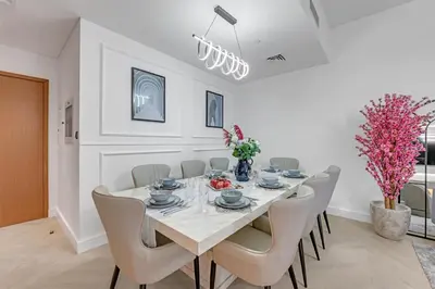 a white dining room with a white table and chairs at Direct Burj & Fountain Views - Designer 4BR Haven! in Dubai