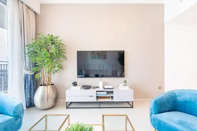 a living room with blue chairs and a tv at Apartment with Stunning Canal Views, Just Minutes from Dubai Mall and Burj Khalifa - 17 Icon Bay, Dubai Creek Harbour by Deluxe Holiday Homes in Dubai