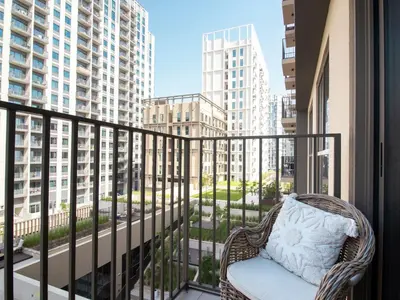 a wicker chair on a balcony with a view of buildings at Modern & Stylish Stay in 1BR Socio Dubai Hills in Dubai