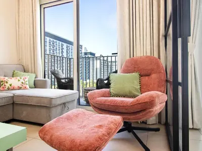 a living room with a chair and a couch at Modern & Stylish Stay in 1BR Socio Dubai Hills in Dubai
