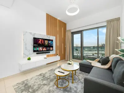 a living room with a couch and a tv at Stylish 1BR Near Burj Khalifa with Rooftop Pool, City Views, Free Parking in Dubai