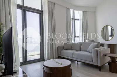 a living room with a couch and a large window at Bloomfieilds Spacious 1br Azizi Fawad in Dubai