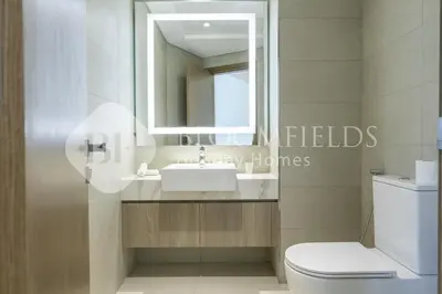 a bathroom with a sink and a mirror and a toilet at Bloomfieilds Spacious 1br Azizi Fawad in Dubai
