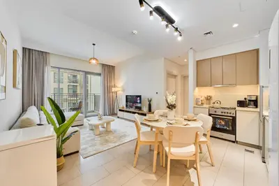 a kitchen and living room with a table and chairs at Your Dubai Hills Retreat 1BR in Park Heights 2 in Dubai