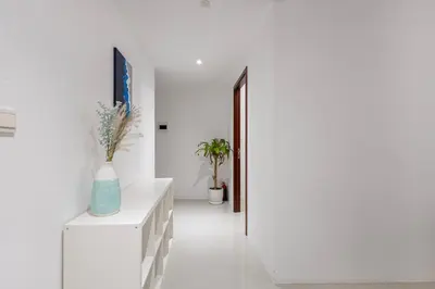 a hallway with white walls and a white console with a vase at Bahar 1, JBR - 2 Bedroom Apartment - Allsopp & Allsopp in Dubai