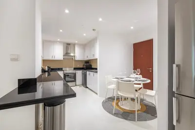 a kitchen with a table and chairs and a refrigerator at Bahar 1, JBR - 2 Bedroom Apartment - Allsopp & Allsopp in Dubai