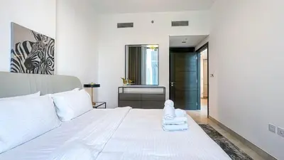a bedroom with a white bed and a bathroom at Modern & Cozy 1BR in Business Bay with Pool View - 10AB05 in Dubai