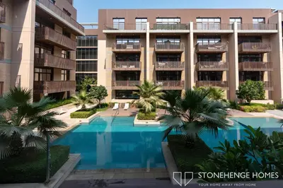 an apartment building with a swimming pool and palm trees at Cozy 1BR in Belgravia , JVC, Pool View, 20 Min from Downtown Dubai in Dubai