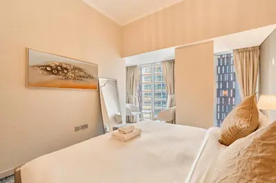 a bedroom with a large white bed with a large window at Twisting Tower Stay a Chic 2BR in Cayan Tower in Dubai