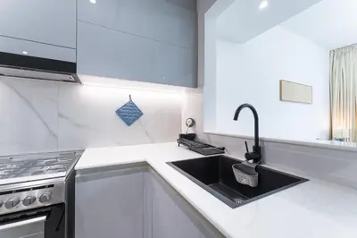 a white kitchen with a sink and a stove at HAVN - Spacious One Bedroom in Binghatti Creek in Dubai