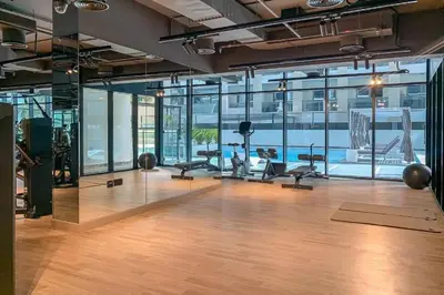 an office with a gym with a pool in the background at HAVN - Spacious One Bedroom in Binghatti Creek in Dubai