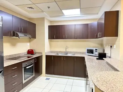 a large kitchen with wooden cabinets and a sink at Cozy apartment in Dubai Marina - Torch Tower in Dubai