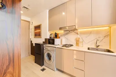 a kitchen with a washing machine and a sink at Bright & Cozy Studio in Vibrant Azizi Riviera in Dubai