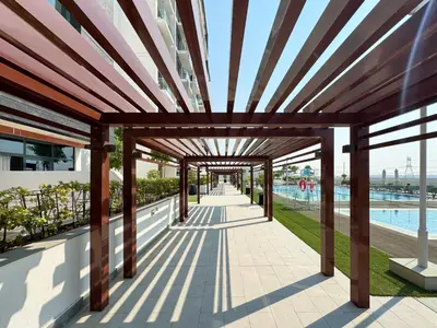 a pergola on the side of a building with a pool at Bright & Cozy Studio in Vibrant Azizi Riviera in Dubai