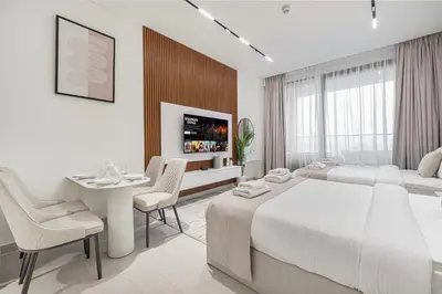 a white bedroom with two beds and a table and chairs at Binghatti Trillionaire! 2 Double Beds! Private Jacuzzi, Prime Location! in Dubai