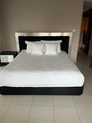 a bed with white sheets and pillows in a room at Cozy private master bedroom for solo female in shared home in Dubai