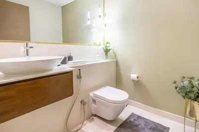 a white bathroom with a sink and a toilet at Chic 2Bedroom And Maids Room Apartment Mins from Dubai Mall in Dubai