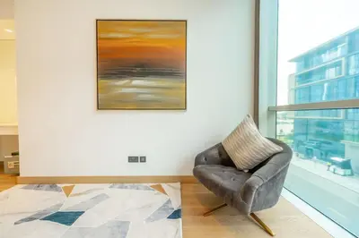 a leather chair in a room with a painting on the wall at Chic 2Bedroom And Maids Room Apartment Mins from Dubai Mall in Dubai