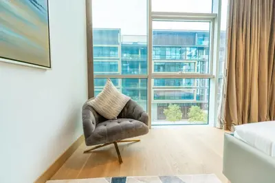 a leather chair in a room with a large window at Chic 2Bedroom And Maids Room Apartment Mins from Dubai Mall in Dubai