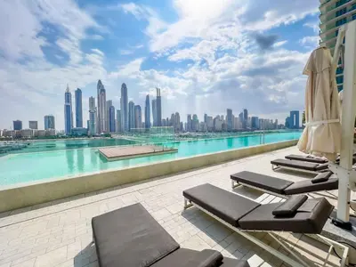 a pool with chaise lounge chairs and a city skyline at Elegant 1BR at Sunrise Bay with Stunning Palm View in Dubai